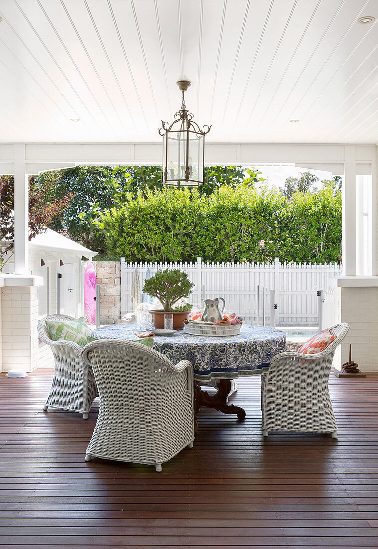 Runder Tisch mit weißen Rattansessels auf überdachter Terrasse
