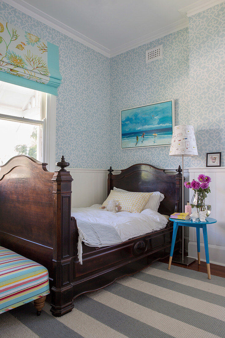 Antikes französisches Bett und blauer Nachttisch im Jugendzimmer mit weiß-blauer Tapete
