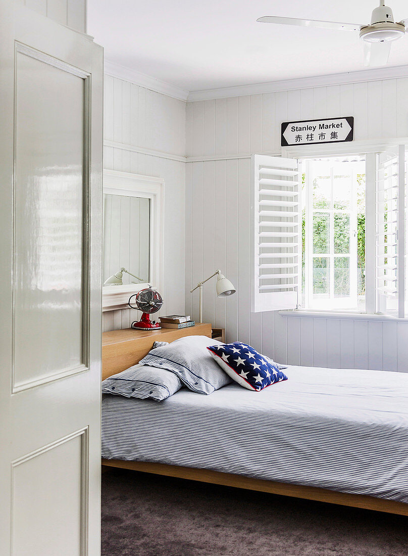 Bett mit Kissen im Zimmer mit weißer Holzverkleidung