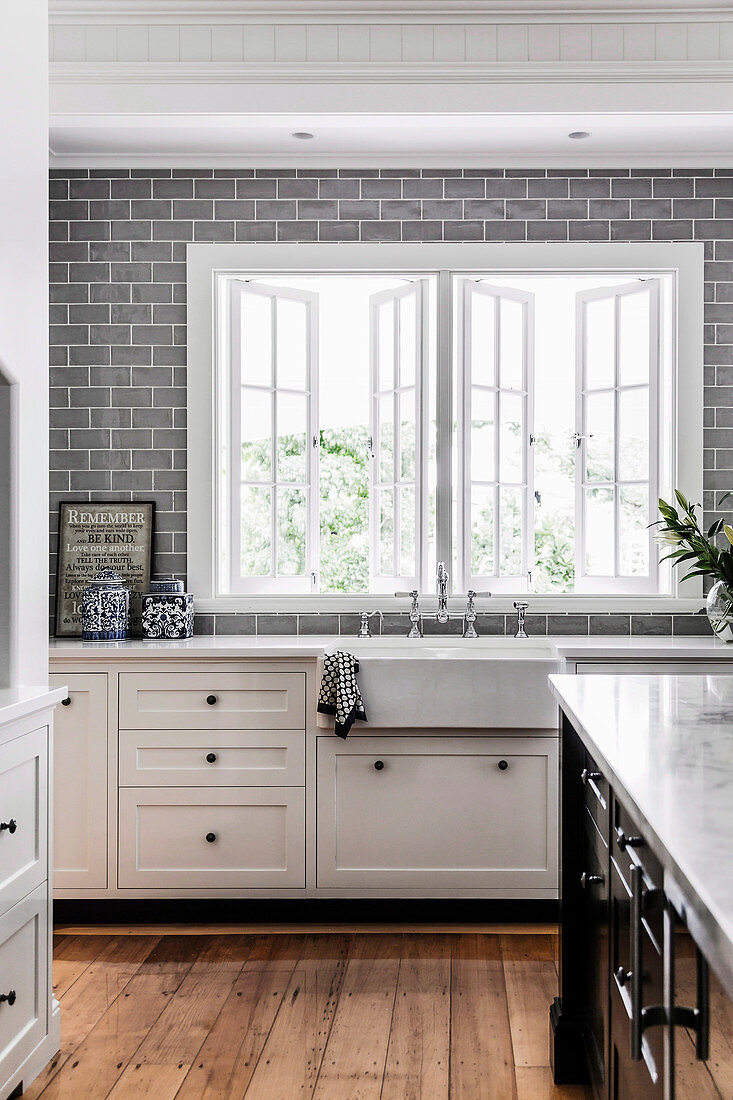 weiße Küchenzeile und graue Wandfliesen in der Küche mit Fenster