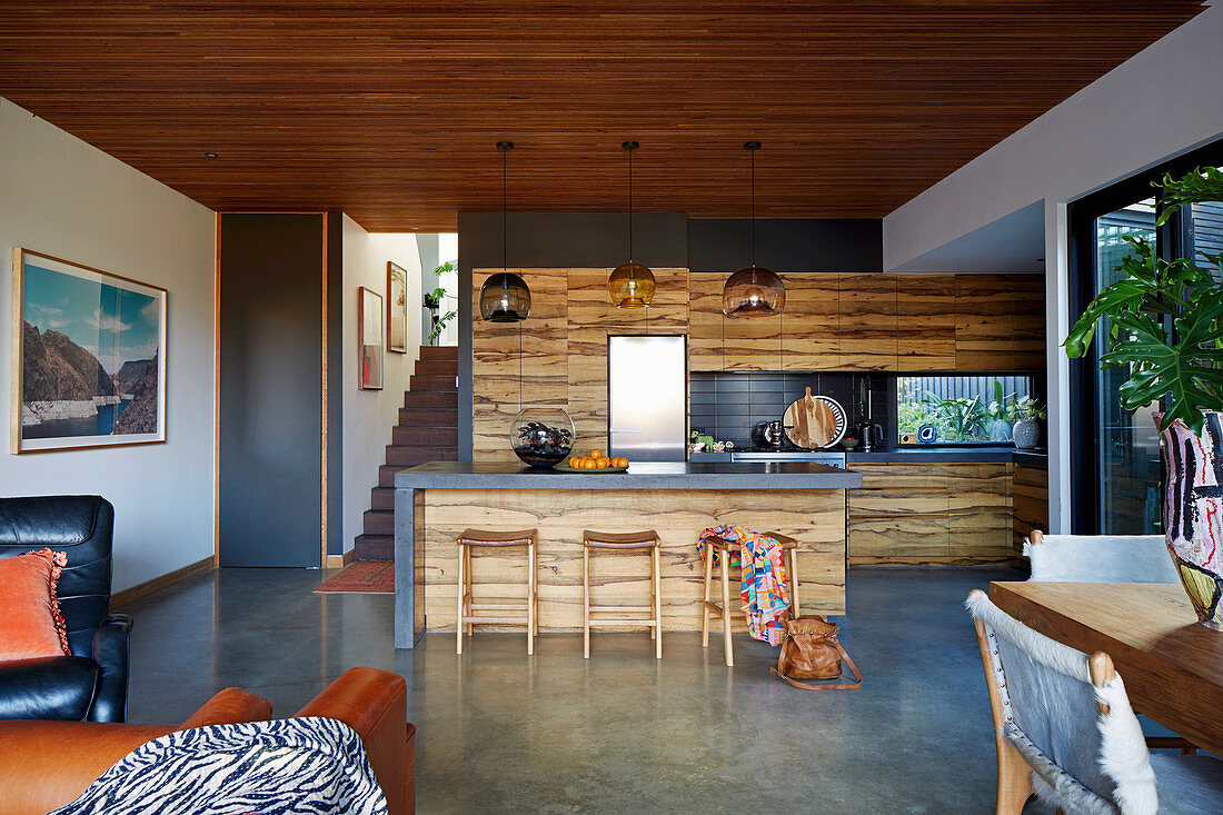 Küche mit Holzfronten in offenem Wohnraum mit Betonboden