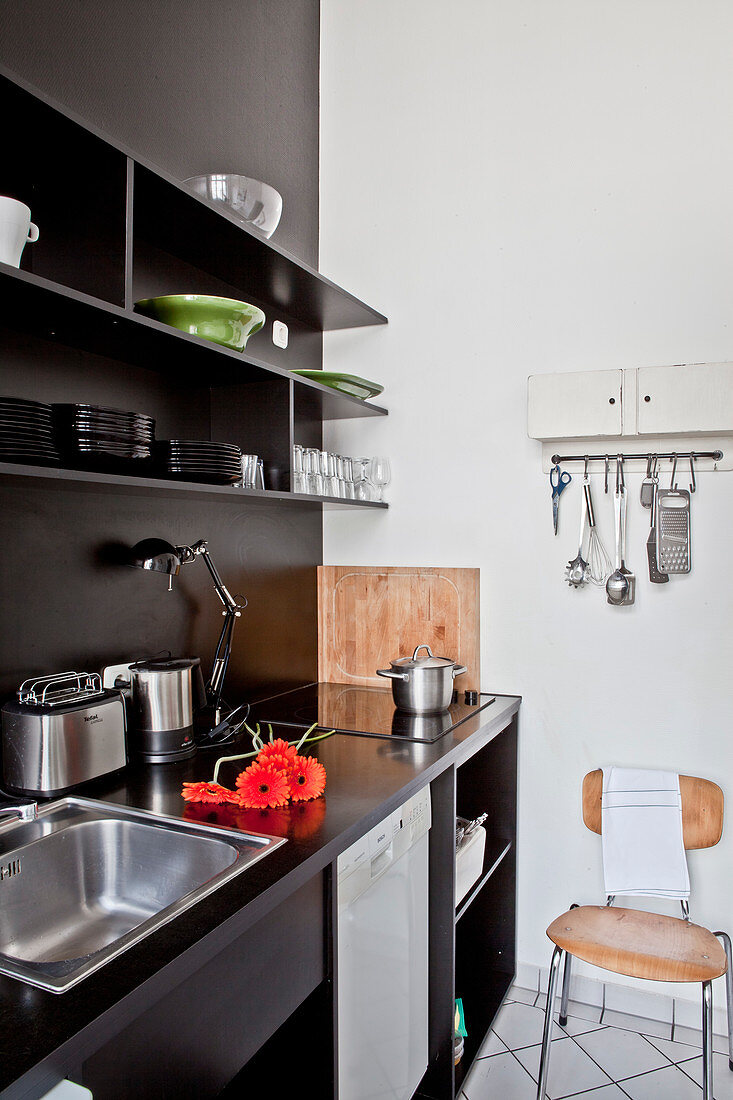 Schwarze Küchenzeile mit offenen Regalen an schwarzer Wand