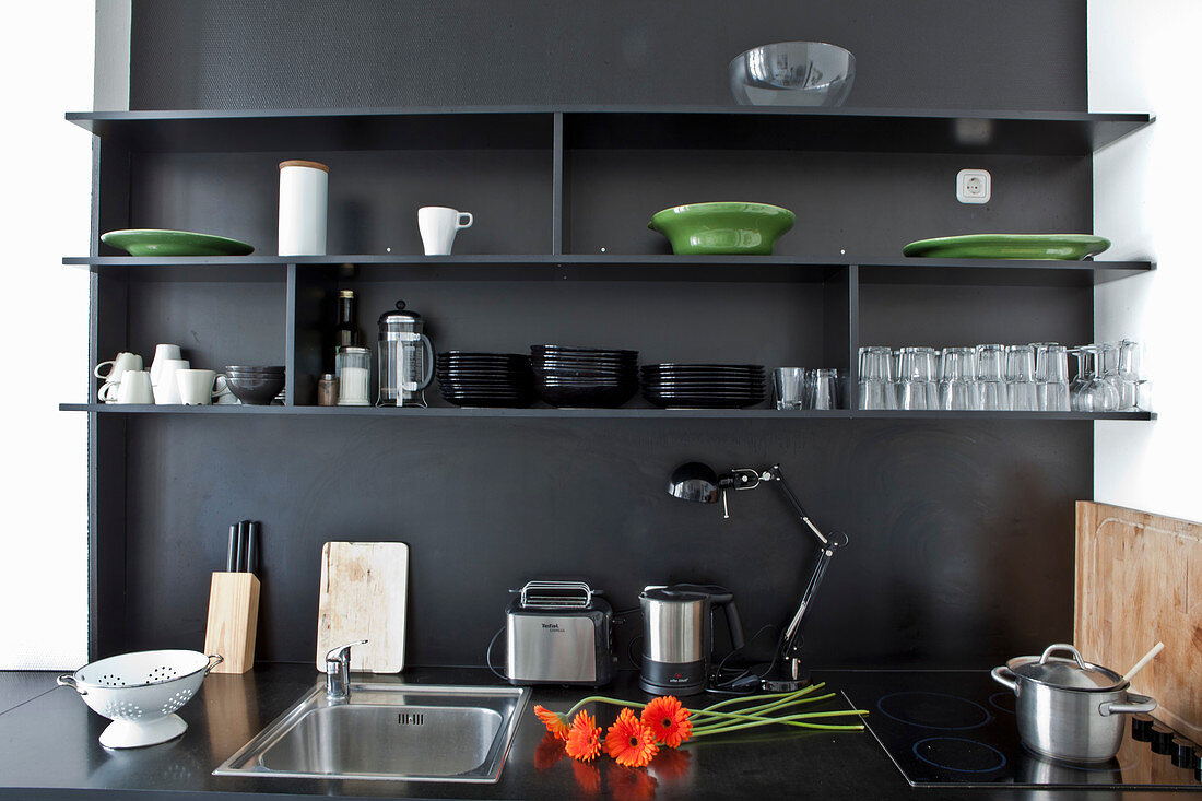 Schwarze Küchenzeile mit offenen Regalen an schwarzer Wand