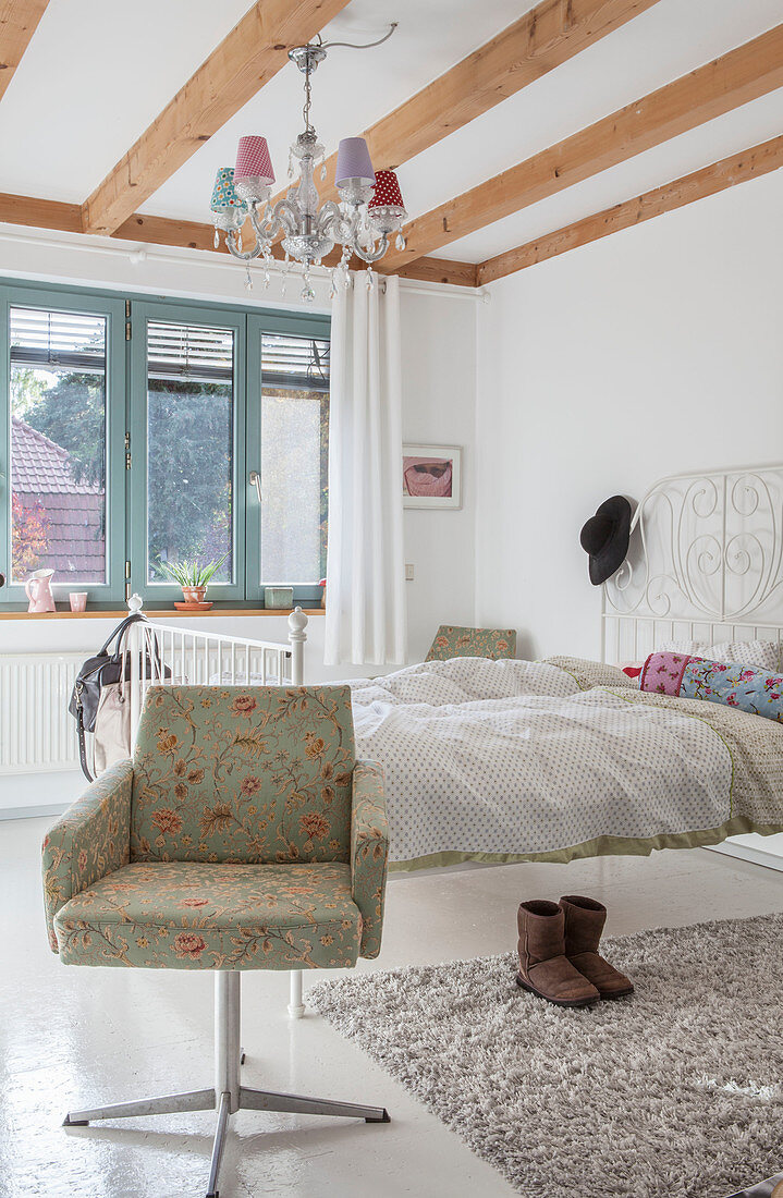 Armchair and white metal bed in bright bedroom