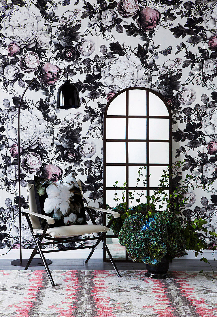 Stuhl und Bodenspiegel vor einer opulenten Blumentapete