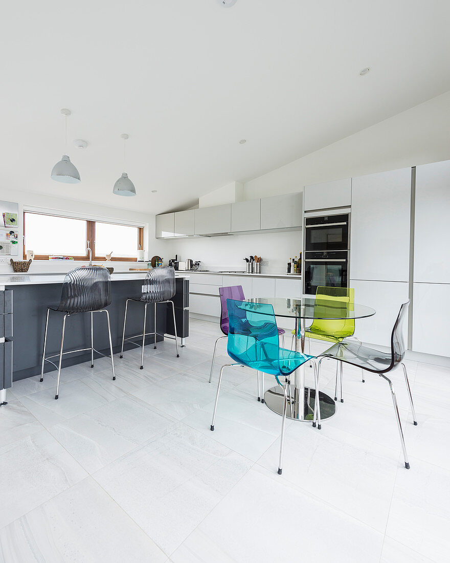 Bunte transparente Stühle um den Esstisch in moderner Küche
