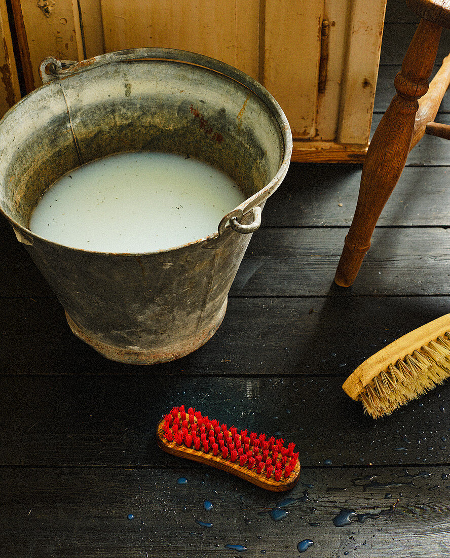 Soapy water in vintage bucket and scrubbing brushes