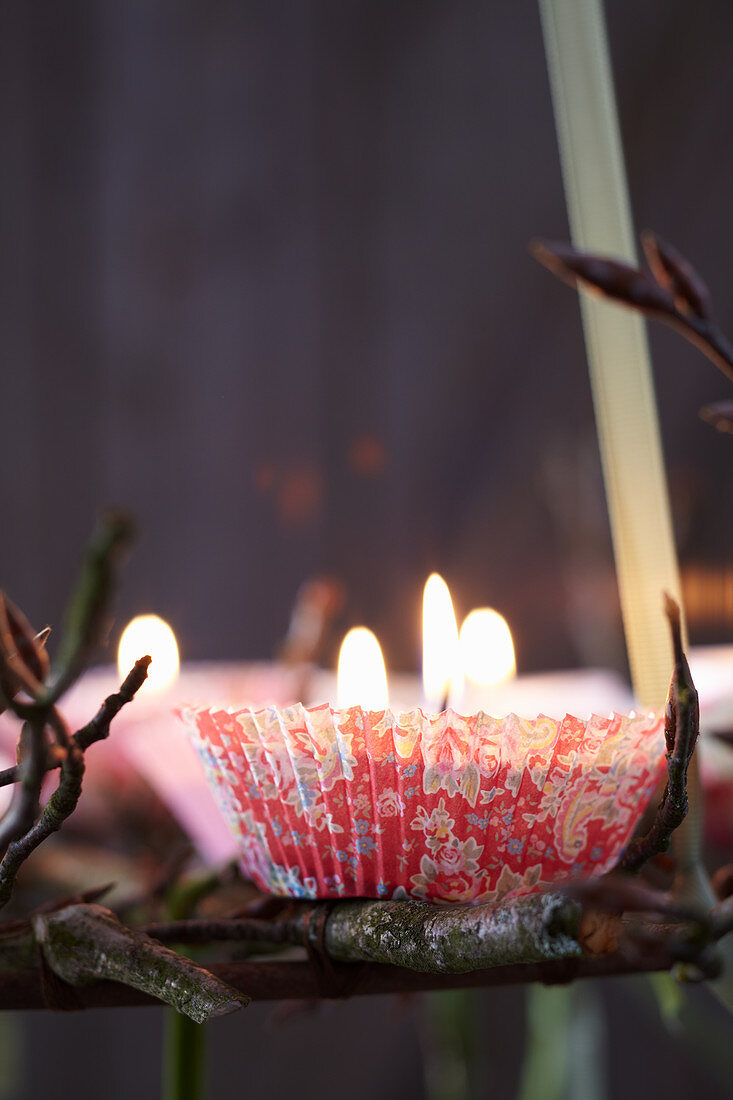 Hängender Adventskranz aus Ästen dekoriert mit Kerzen in Papierförmchen (Nahaufnahme)