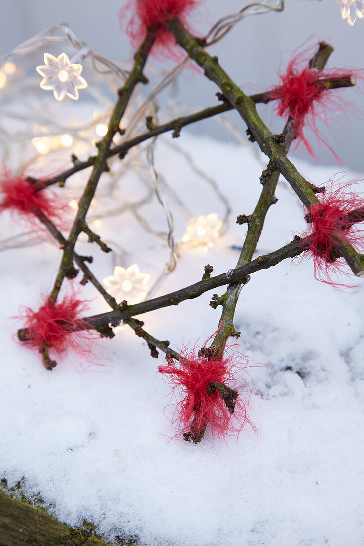 Handmade twig star and fairy lights in snow