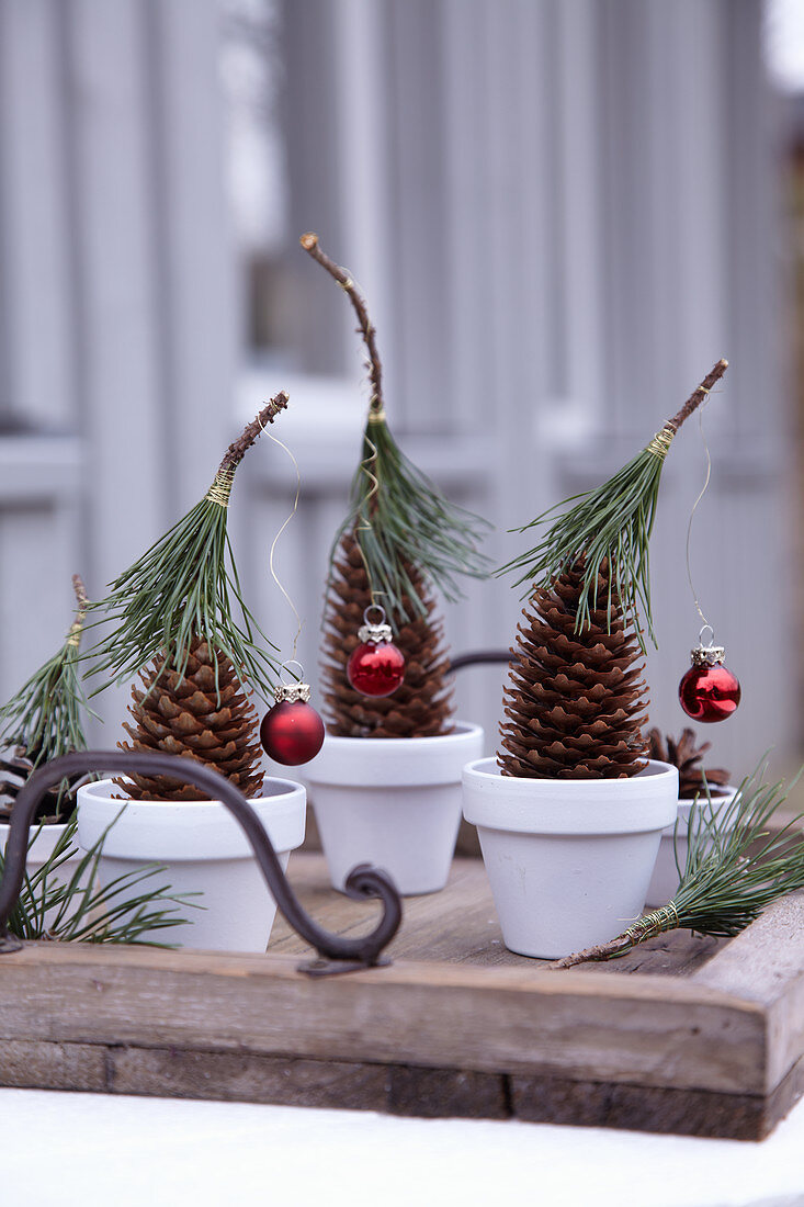 Tannenzapfen weihnachtlich dekoriert mit Kieferhütchen und Mini-Baumkugeln