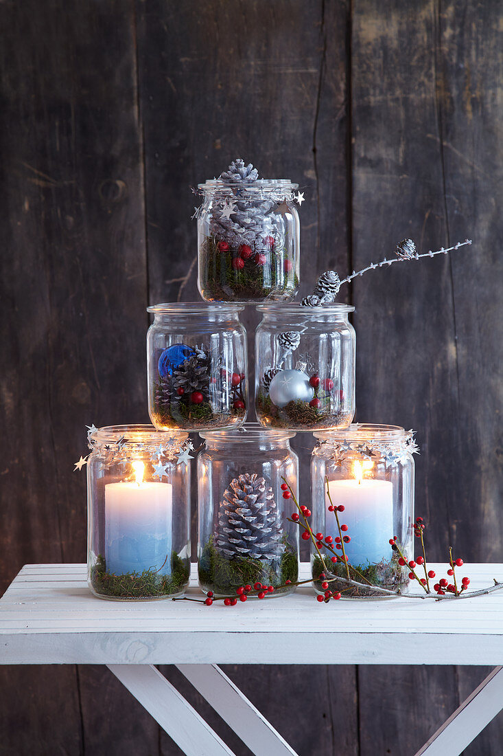 Pyramid of festive mason-jar candle lanterns decorated with natural materials