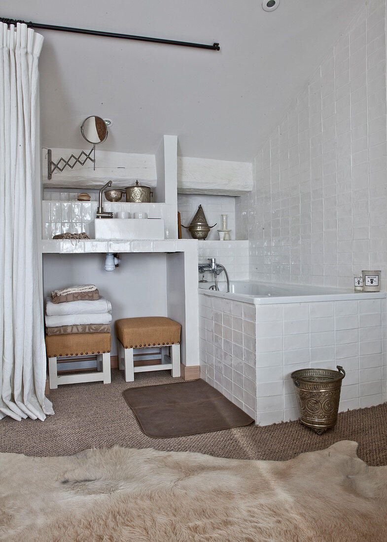 Badewanne im Badezimmer mit weißen Wandfliesen und Tierfellteppich