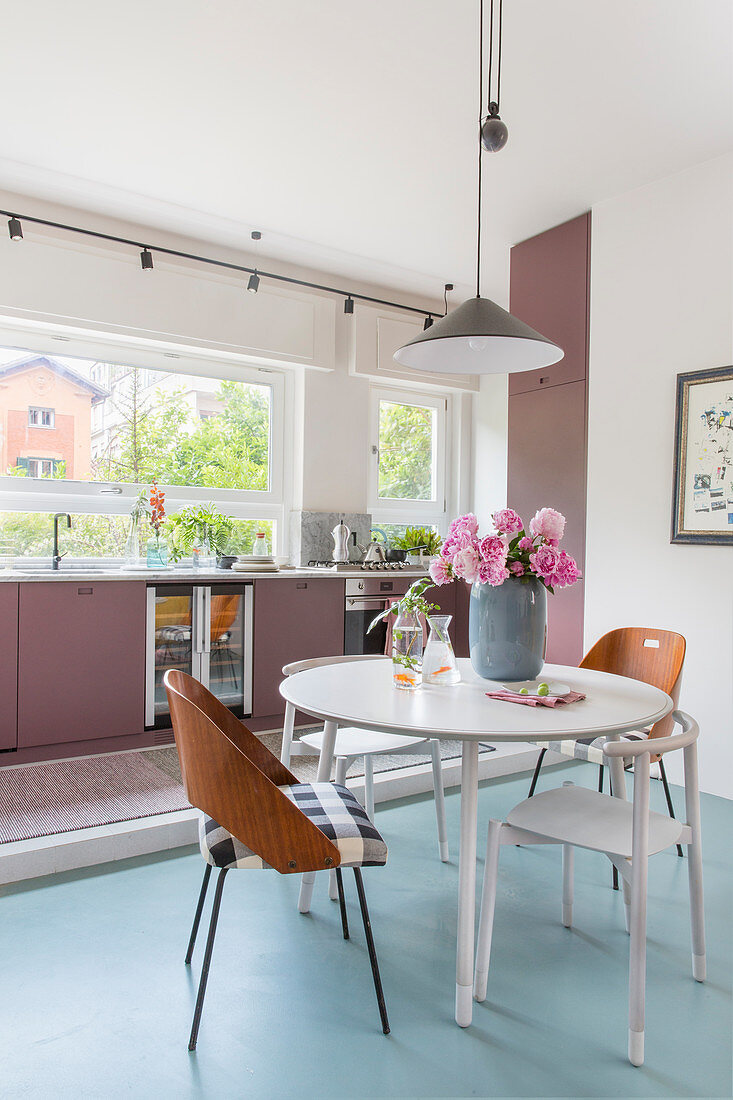 Various chairs around table in front of kitchen counter with dusky-pink cabinets