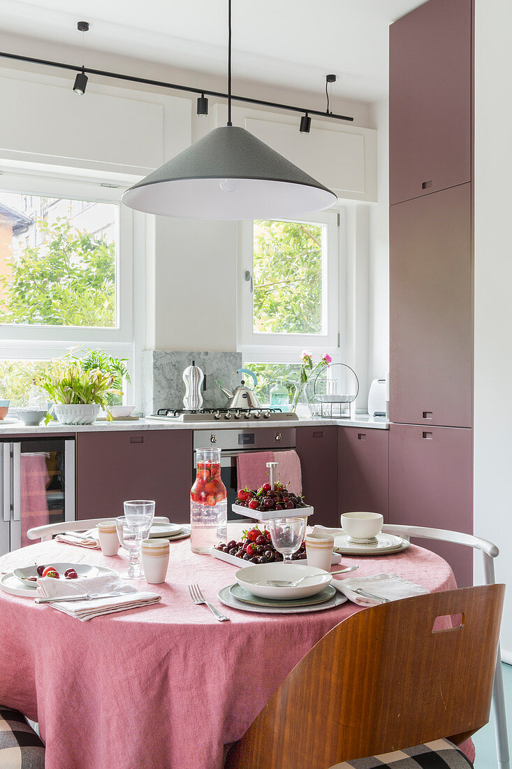 Set table in kitchen-dining room with dusky-pink cabinets