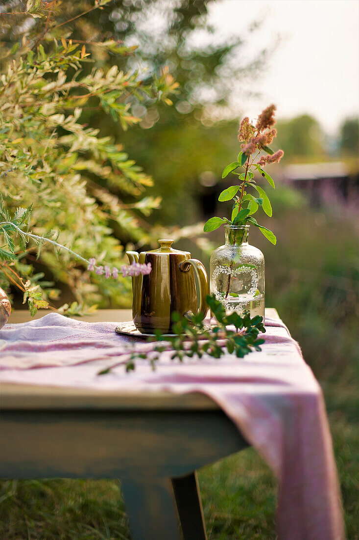 Kanne und Vase auf dem Tisch im spätsommerlichen Garten