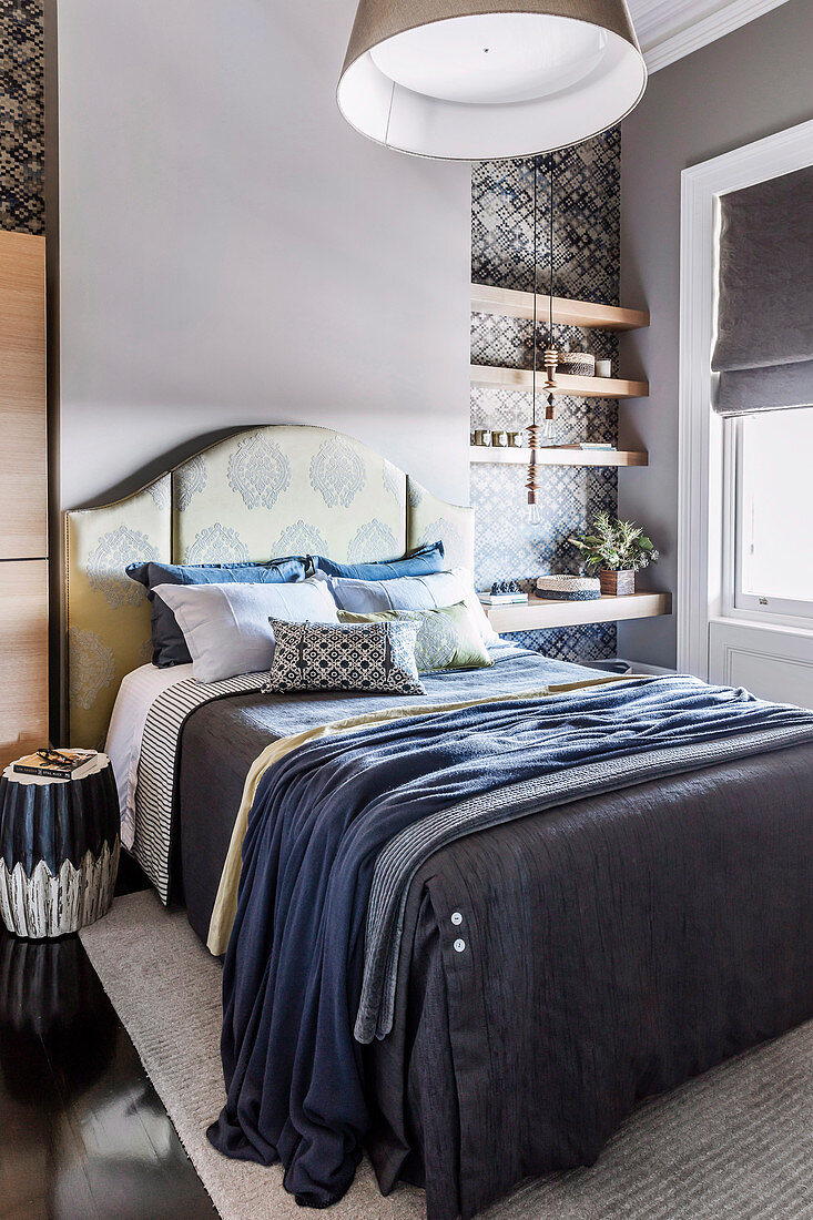 Bed with accessories in blue tones and clamped shelves in the bedroom
