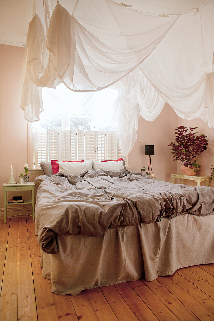Canopy above double bed in bedroom with wooden floor