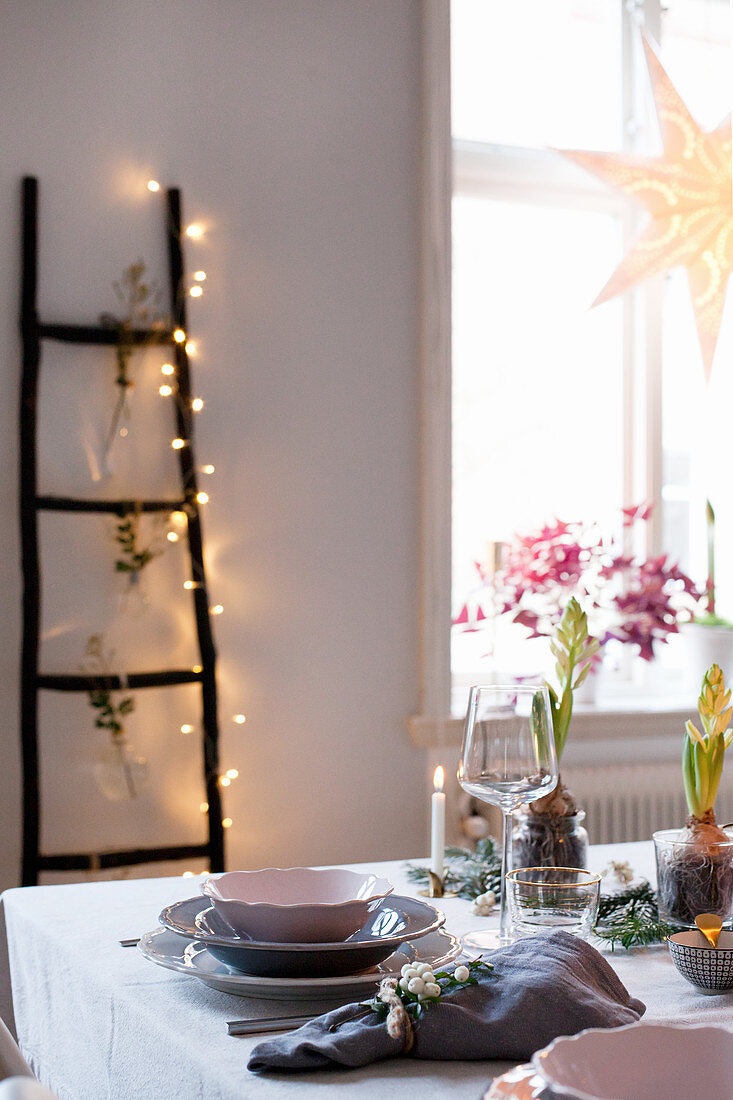 Weihnachtlich gedeckter Tisch und eine Dekoleiter mit Lichterkette