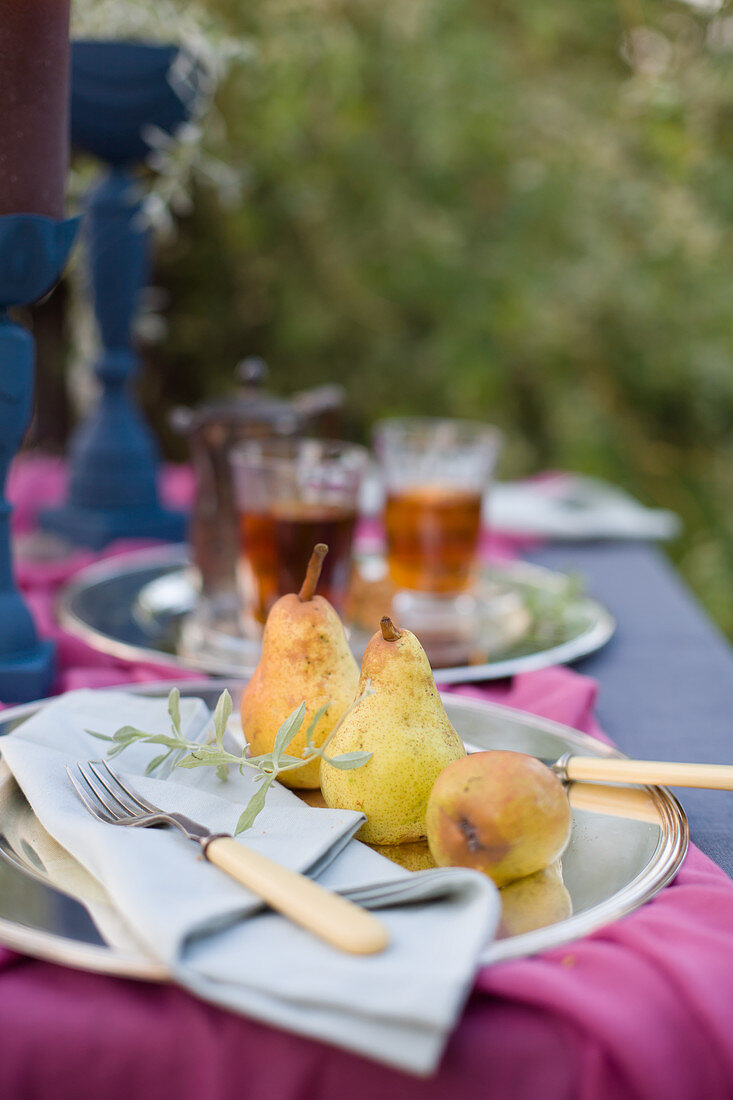 Gedeckter Tisch mit Birnen und Tee im Garten