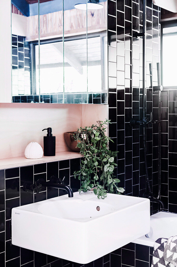 White sink and mirror cabinet in the bathroom with black wall tiles