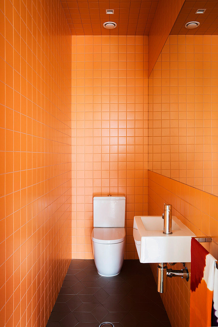 Gäste-Toilette mit orangefarbenen Wandfliesen