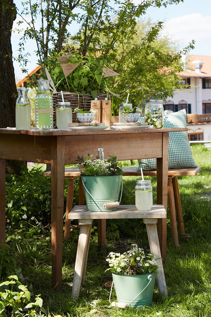 Holztisch und Hocker mit Getränken für eine Gartenparty