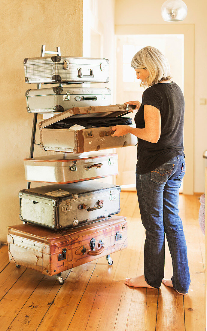 Blonde Frau vor DIY-Aufbewahrungsschrank aus Vintage Koffern und Metallgestell