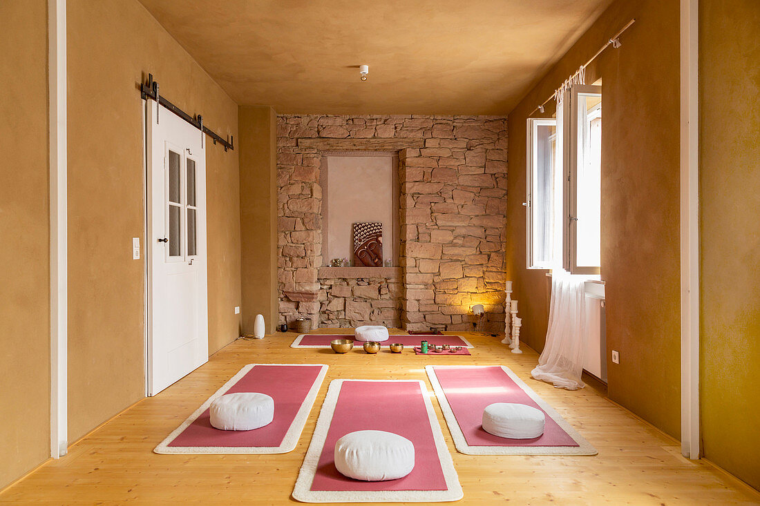 Pink yoga mats and cushions in room with mustard-yellow walls