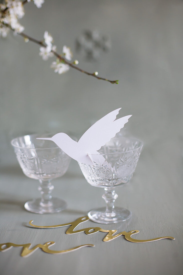 Paper hummingbird in vintage wine glass