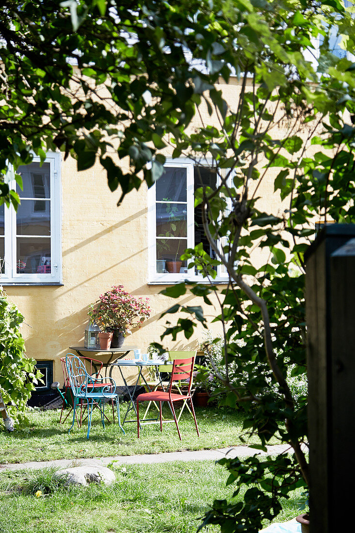 Gartentisch und Stühle am Haus in sonnigem Garten