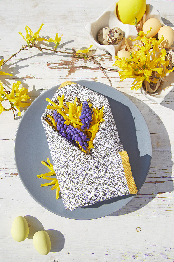 Spring flowers in folded napkin envelope decorating Easter table