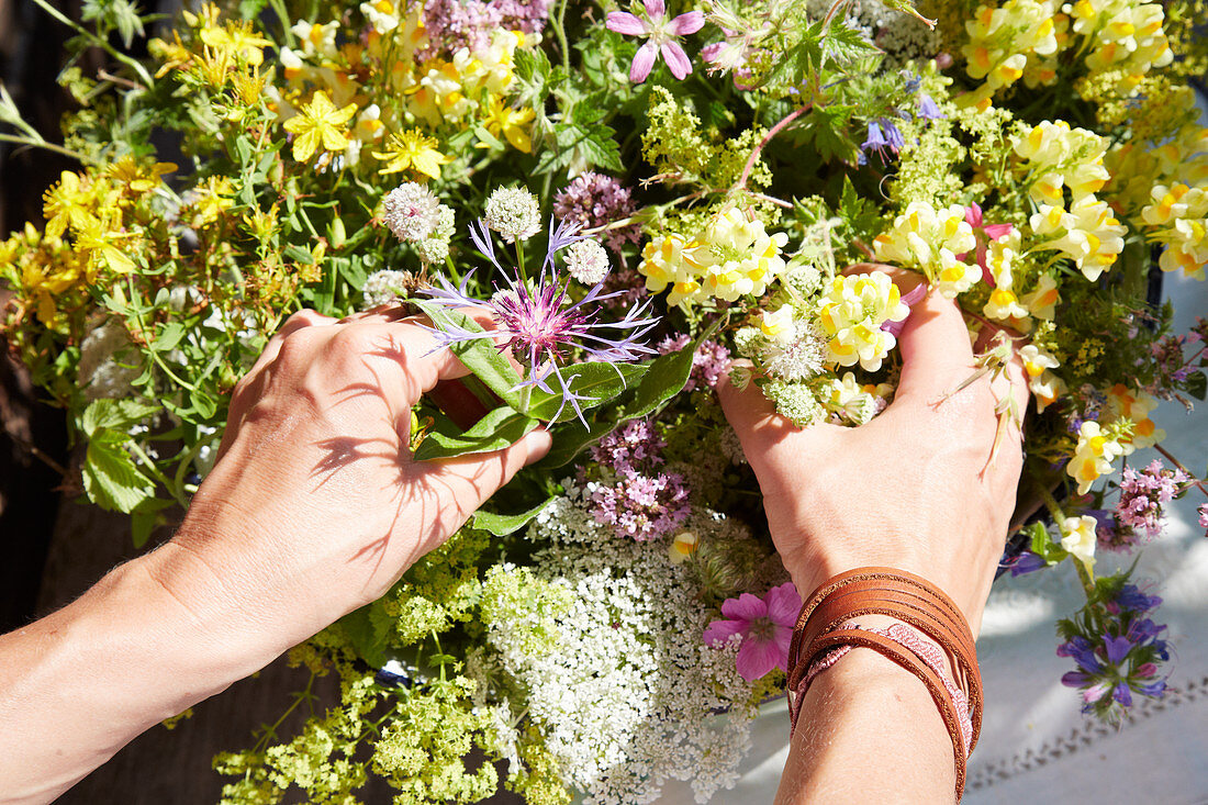 Hände arrangieren Wiesenblumenstrauß