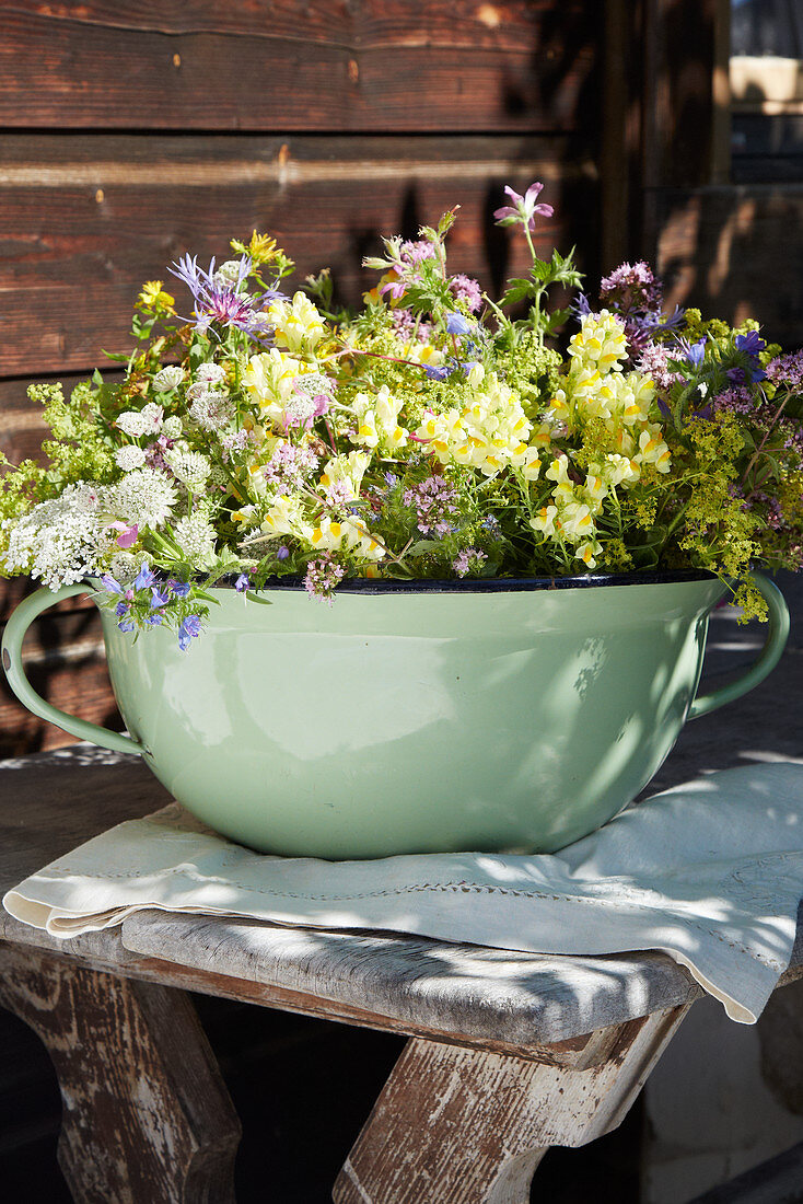 Lady's mantle, cow parsley, flax and cranesbill in green pot with handle