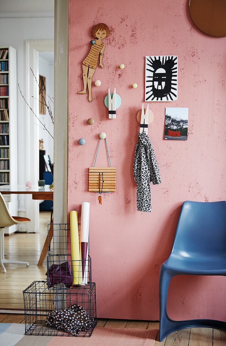 DIY coat rack made from coat hooks and oversized clothes pegs on pink wall