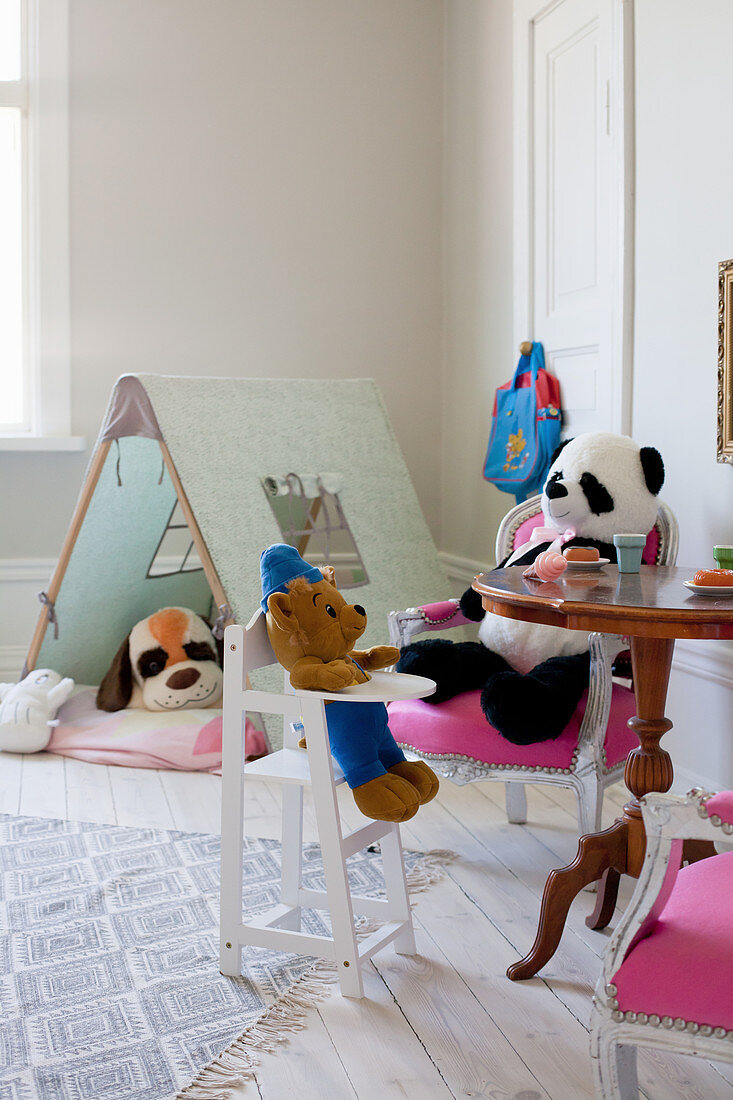Soft toys seated at table and in tent in child's bedroom