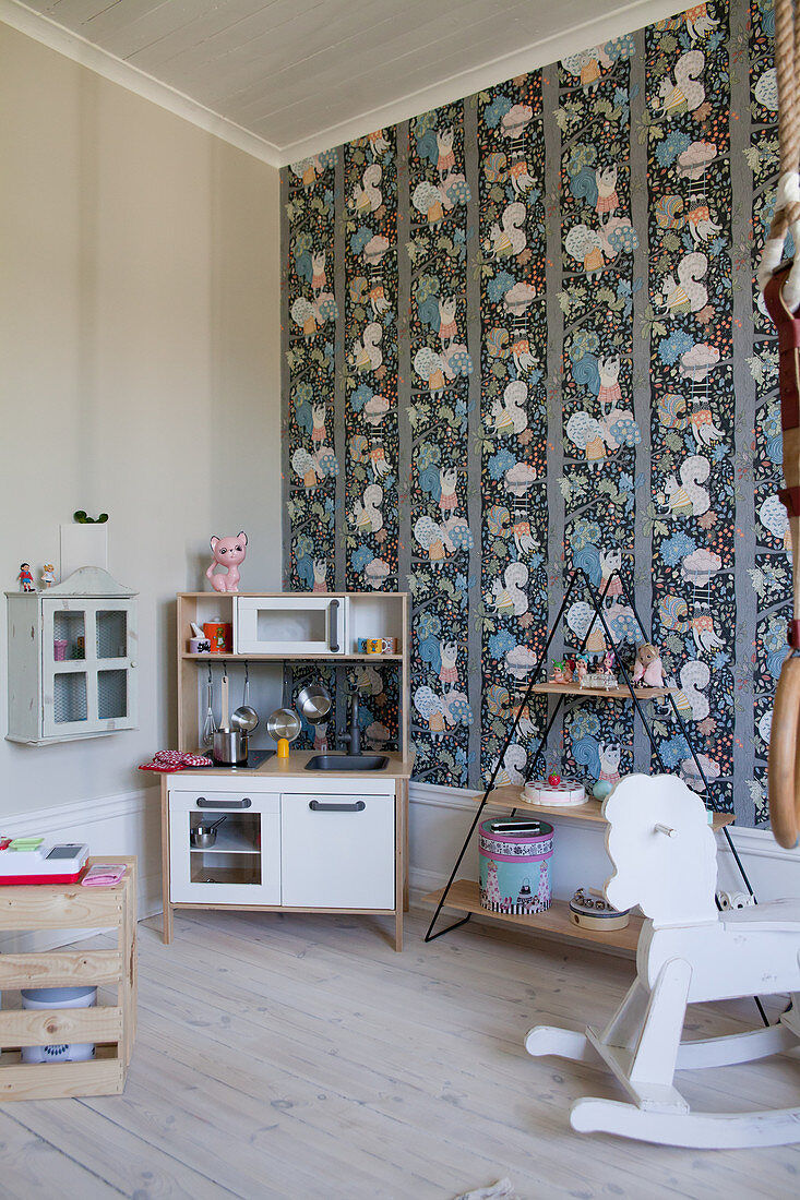 Kinderküche, Regal und Schaukelpferd im Kinderzimmer mit bunter Tapete