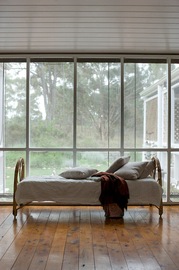 Rattan couch next to glass wall with garden view