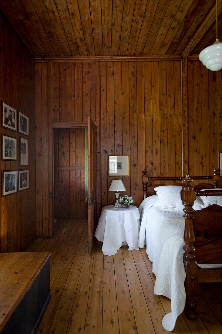 Mit Holz verkleidetes, nostalgisches Schlafzimmer mit altem Bett