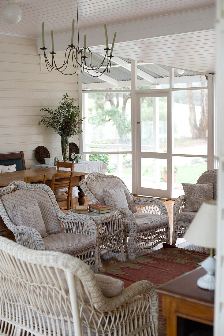 Wicker furniture in classic living room with large windows overlooking garden