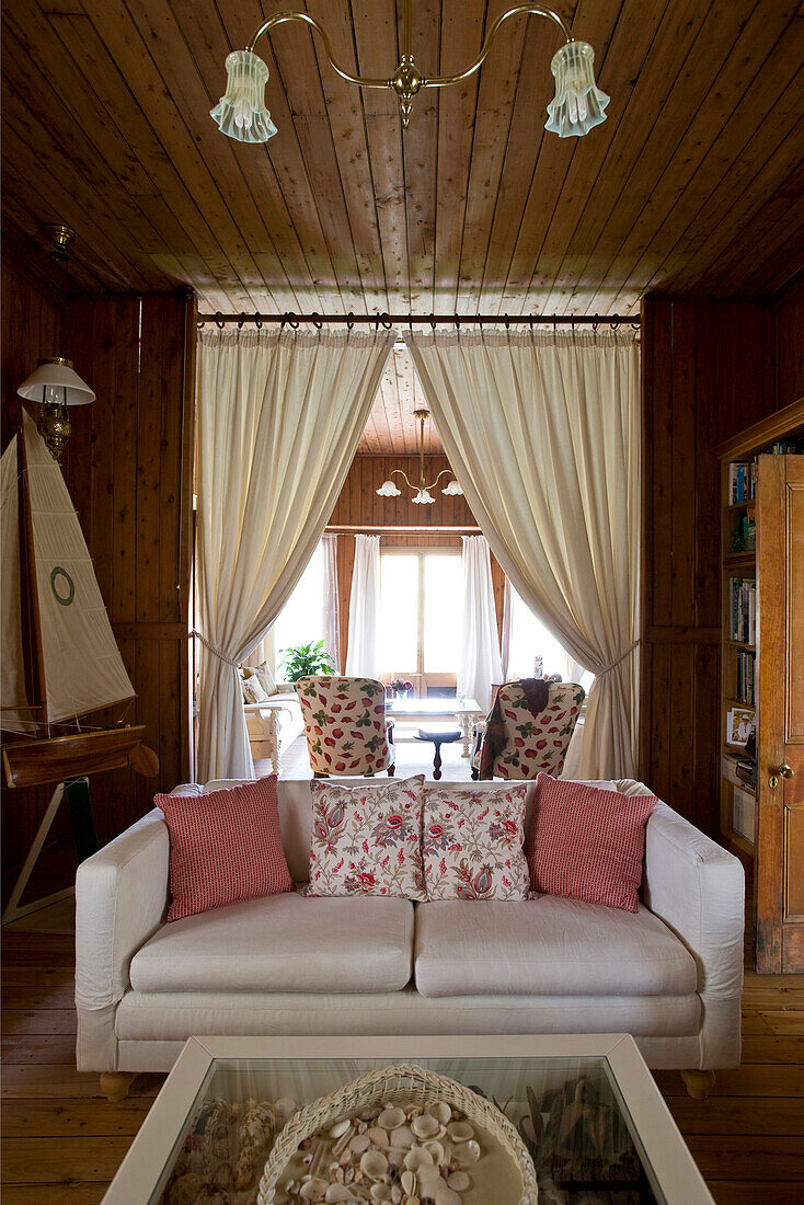 Sofa in front of open doorway with curtains leading into living room