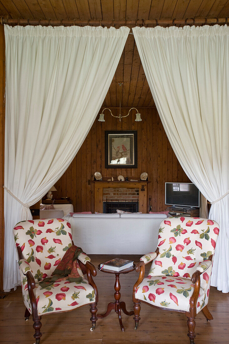 Two armchairs in front of open doorway with curtains leading into living room