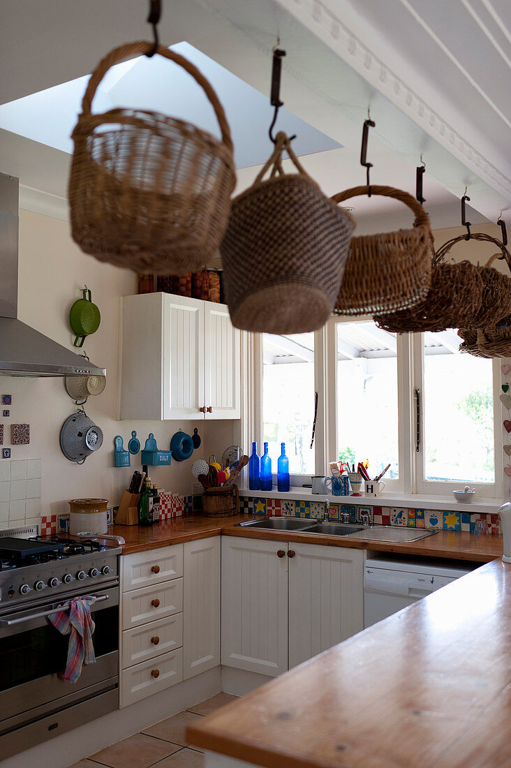 Körbe hängen über der Theke in der Landhausküche mit Oberlicht