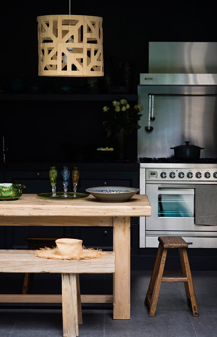 Rustikaler Holztisch mit Hocker und Bank in schwarzer Küche