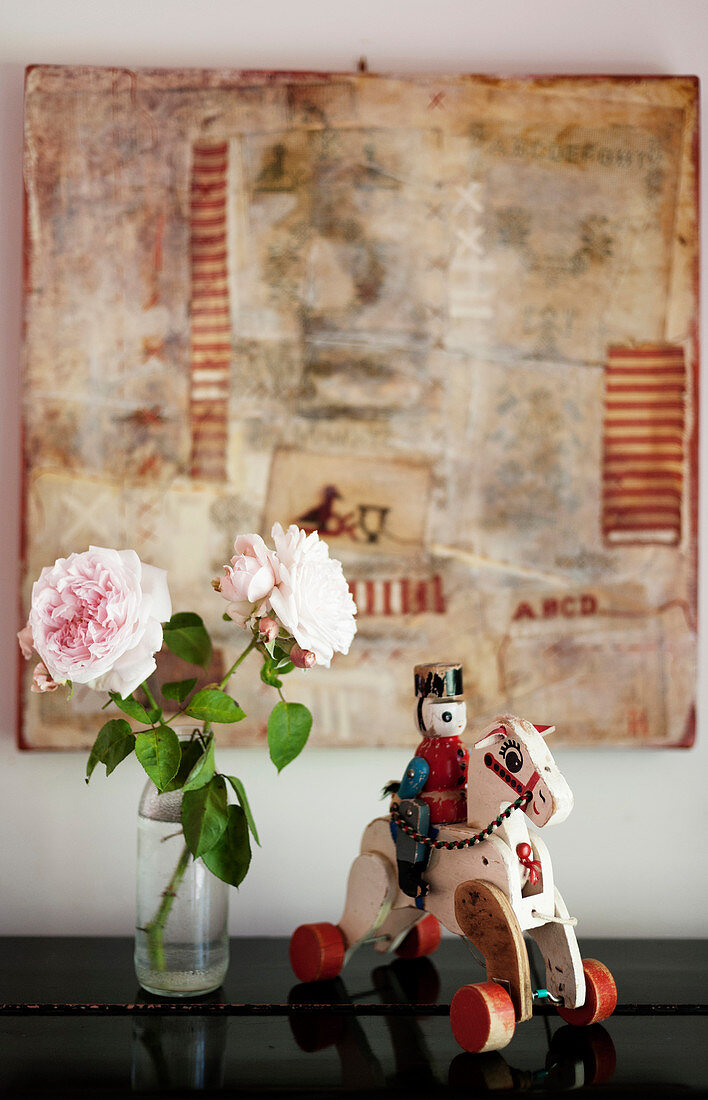 Nostalgischer Spielzeug-Reiter und rosafarbene Rosen vor einer Collage