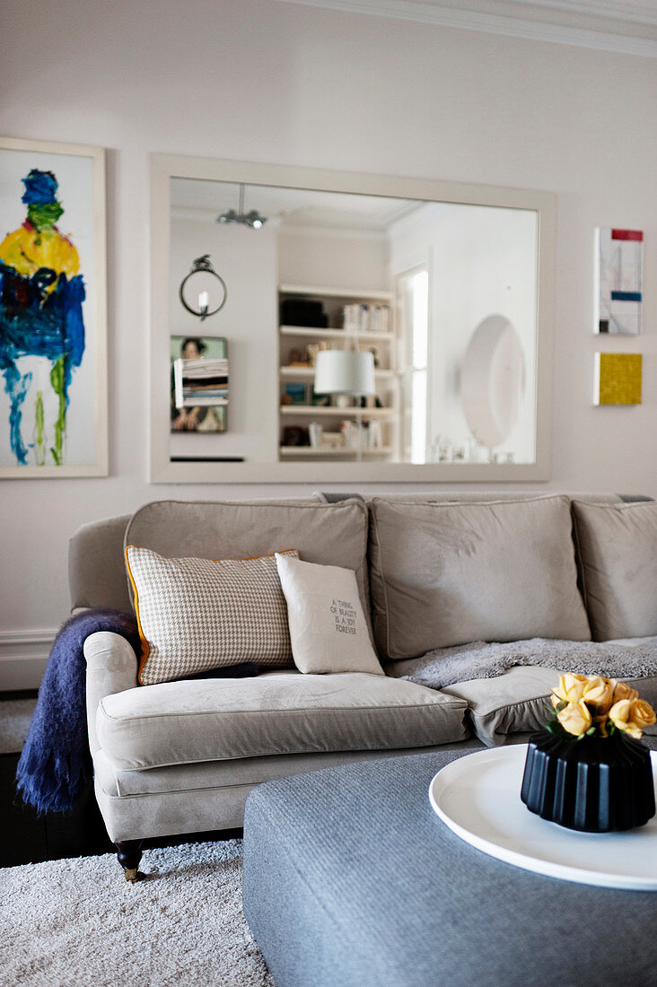 Hellgraues Sofa vorm Wandspiegel im klassischen Wohnzimmer