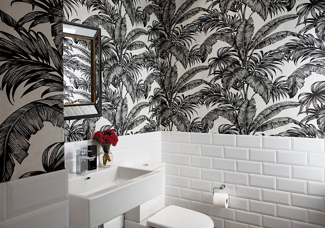 Tapete mit botanischem Muster und weiße Wandfliesen in der Gäste-Toilette