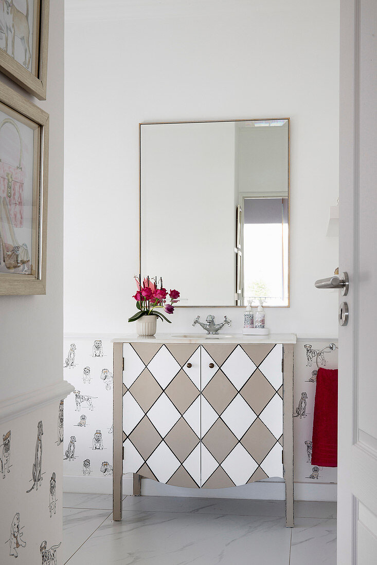 Washstand with diamond patterned front below wall-mounted mirror in bathroom