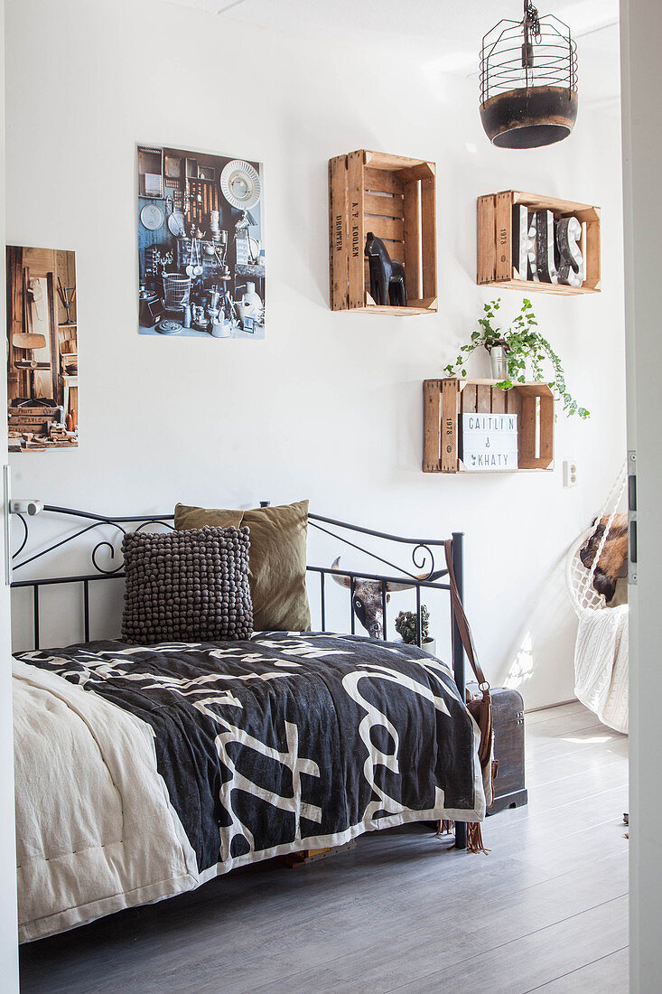 Old wine crates used as shelving modules and metal bed in teenager's bedroom
