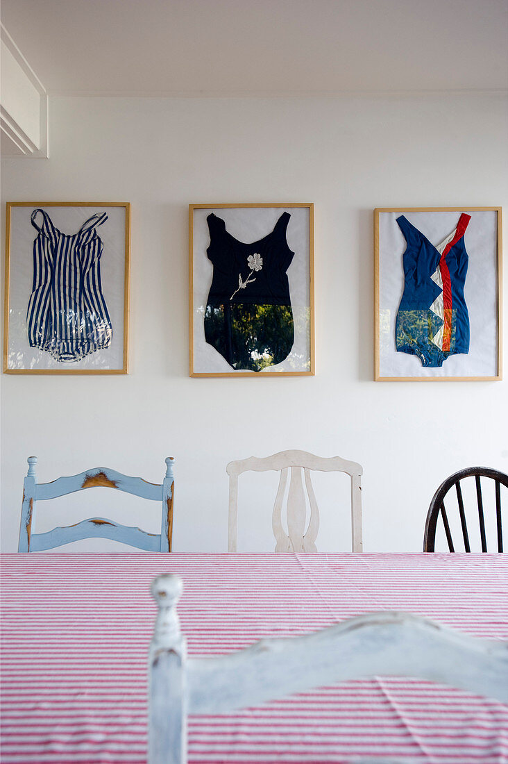 Framed bathing suits behind various chairs in dining room