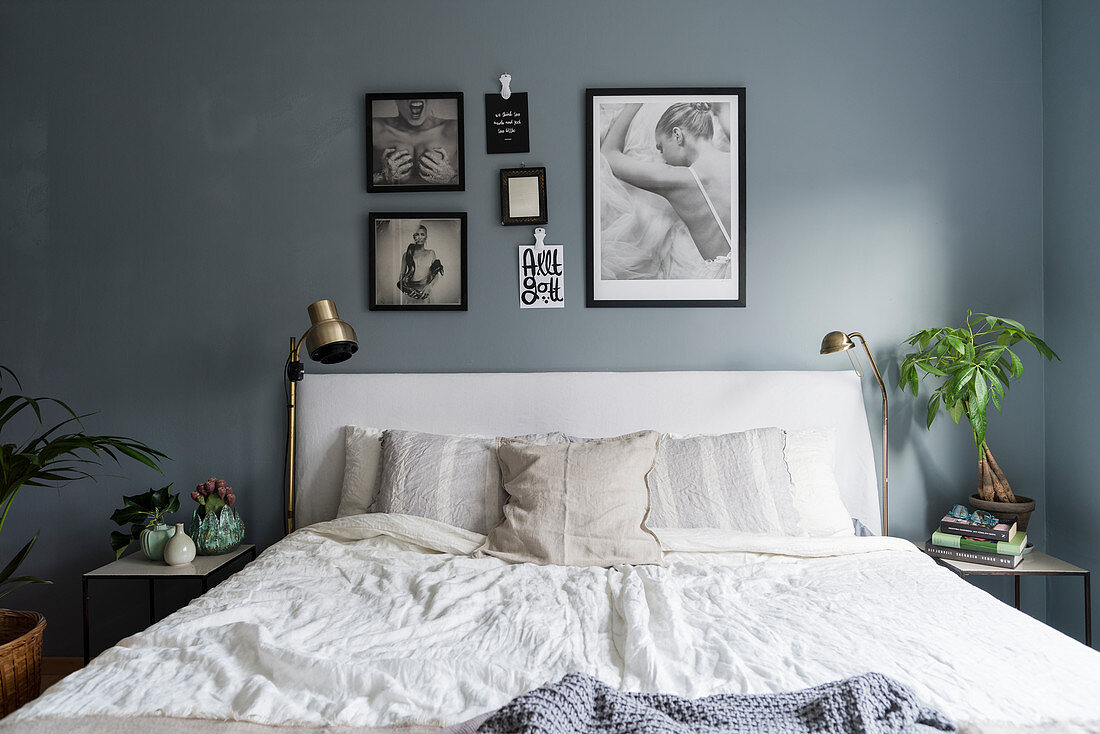 Doppelbett mit weißer Bettwäsche im Schlafzimmer mit blau-grauer Wand